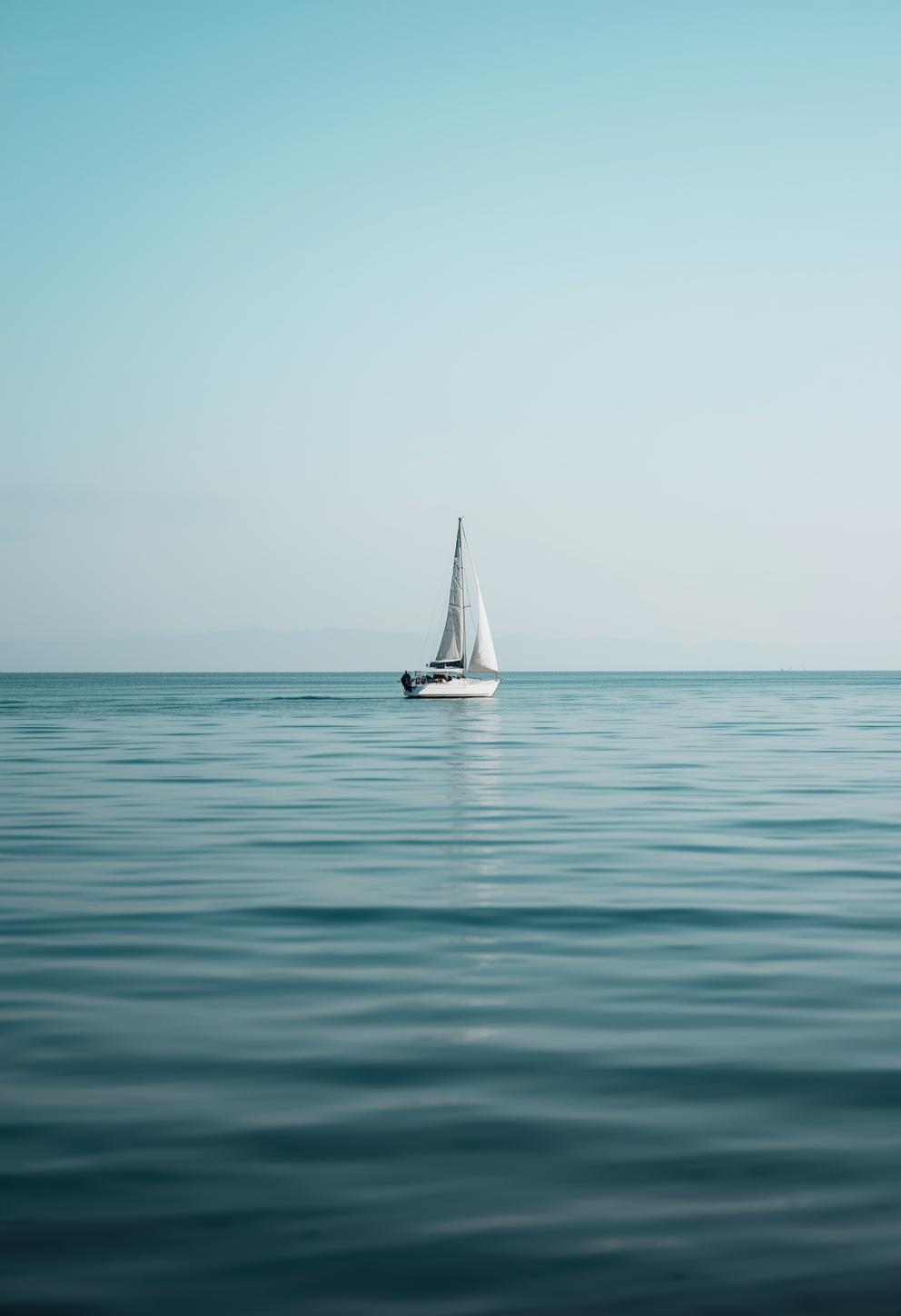 Veleiro solitário navegando em mar aberto e calmo, com amplo horizonte